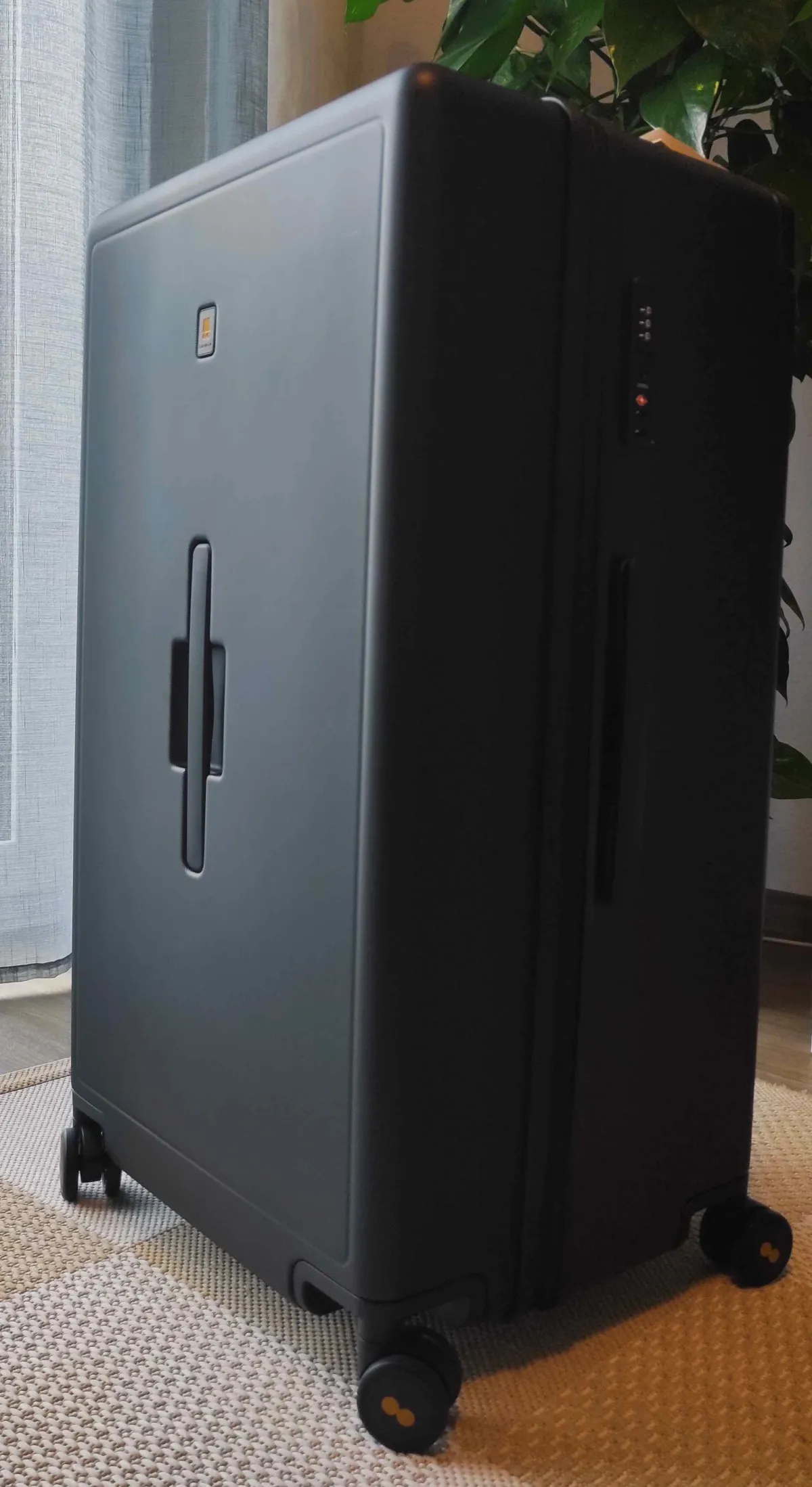 Level8 Voyageur 28 Zoll Koffer in Schwarz, stehend mit sichtbaren Doppelrollen und gelben Akzenten