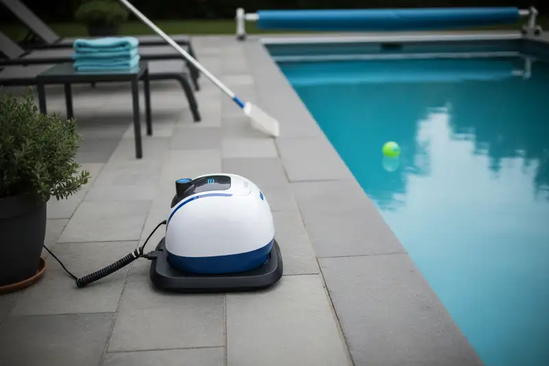 Akku-Poolroboter auf Steinplatten neben einem Pool beim Aufladen
