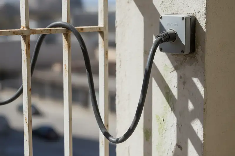 Kabel eines Steckersolargeräts in einer Außensteckdose - der Schuko-Stecker ist seit Dezember 2025 offiziell normiert