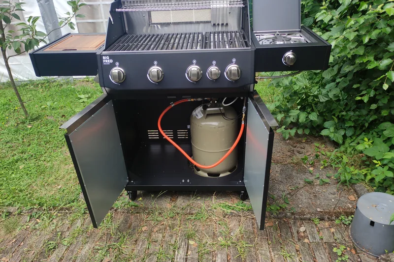 Geöffneter Unterschrank des Big FRED Deluxe mit eingesetzter 11-kg-Gasflasche und Schlauchführung