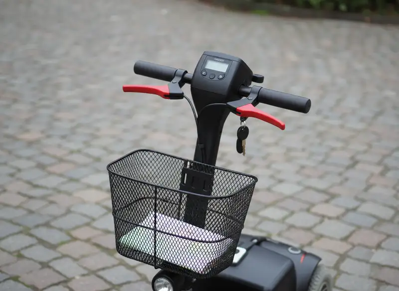 Tillersteuerung eines Elektromobils mit roten Wigwag-Paddeln, zentralem LCD-Display, Zündschloss und Front-Korb
