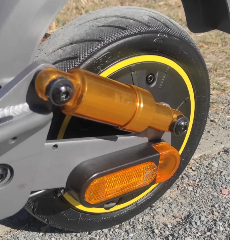 Nahaufnahme des EV10S-Max-Hinterrads mit goldfarbenem Federbein, gelbem Felgenring und seitlichem Reflektor