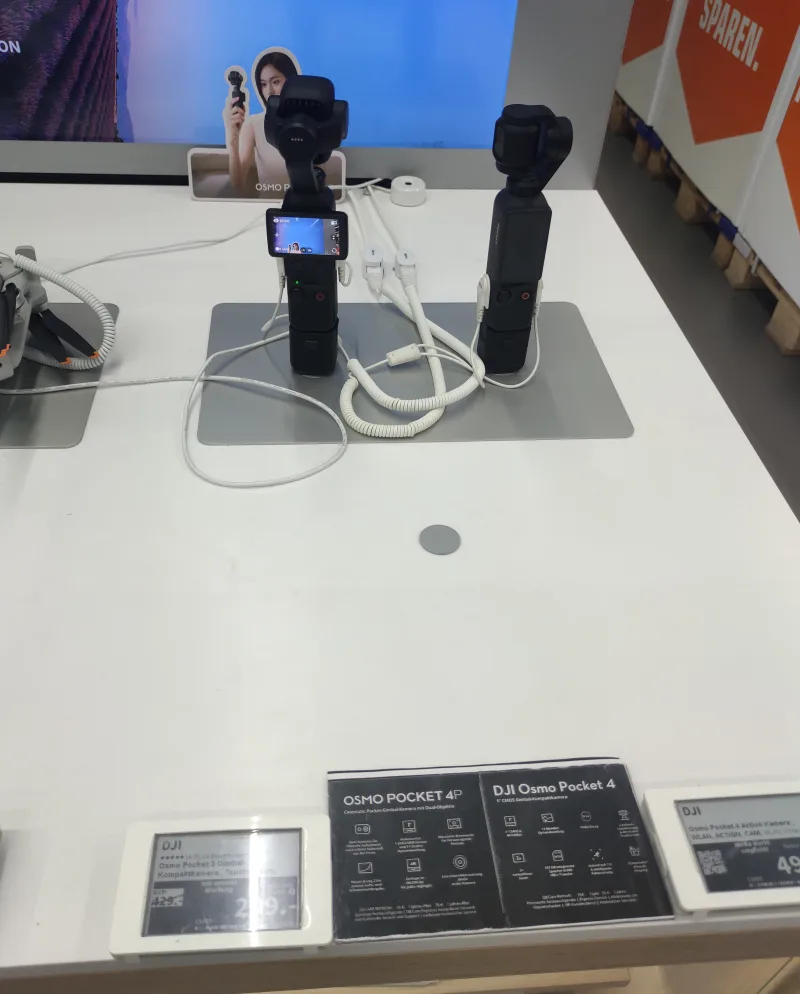 DJI Osmo Pocket 4P und Pocket 4 auf der Aktionsfläche eines Elektromarkts, daneben das Preisschild des Osmo Pocket 3 im Abverkauf