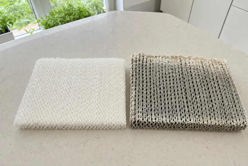 Neue und verkalkte Filtermatte eines Verdunsters nebeneinander auf einer Küchenarbeitsplatte