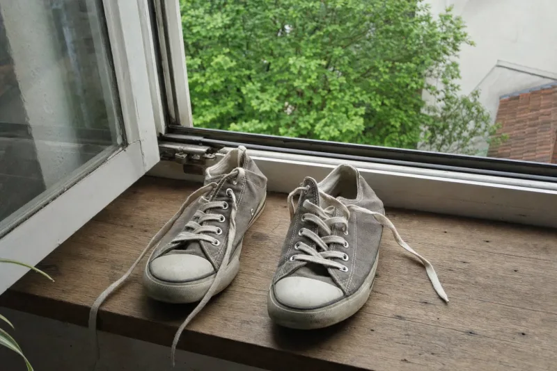 Atmungsaktive Stoffsneaker lüften auf einer Fensterbank bei Tageslicht