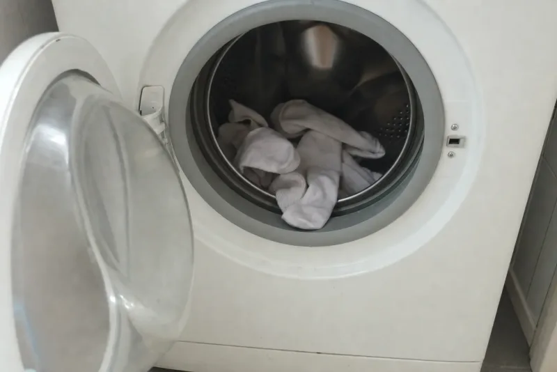 Weiße Baumwollsocken in der offenen Trommel einer Waschmaschine