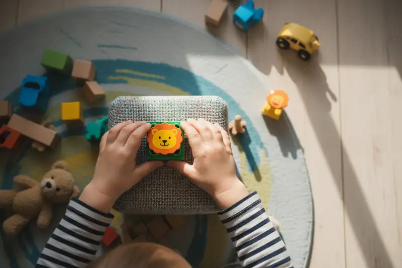 Kinderhände stellen eine bunte Figur auf eine Hörbox im Kinderzimmer