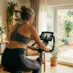 Heimtrainer und Ergometer im Test-Check 12/2025: Fit statt Fehlkauf Eine ältere Frau trainiert auf einem Heimtrainer und schaut auf einem Tablet ein Fitness-Video. Sie trägt Sportkleidung und trainiert in einem hellen Raum.